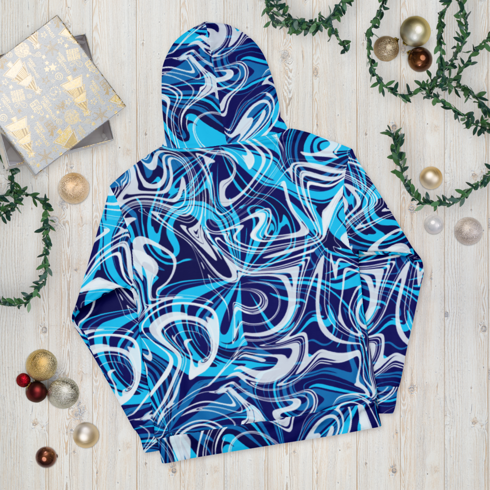 A blue, white, and navy abstract swirl patterned hoodie laid flat on a light wooden surface. The design features bold, fluid lines creating a modern , artistic effect across the entire hoodie. The image shows the back view, highlighting the hood and seamless all-over print. Festive ornaments and greenery are placed around the hoodie for decorative styling.