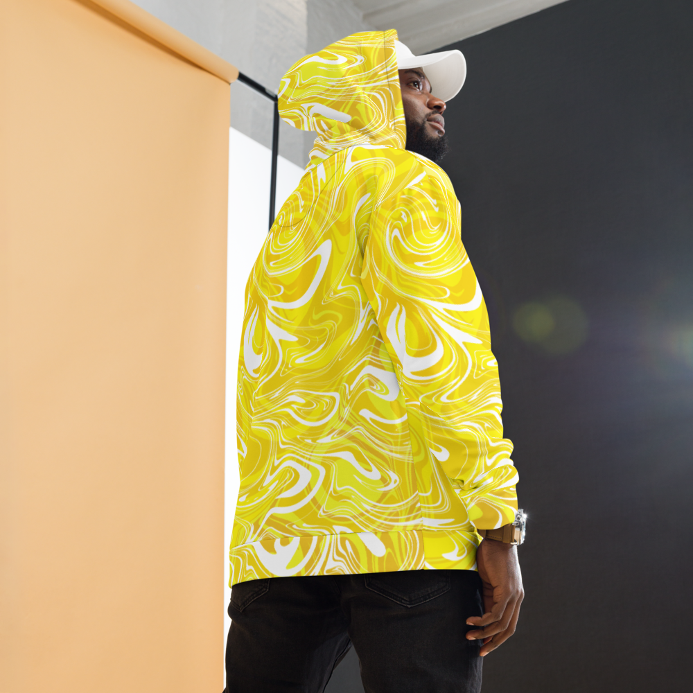 A man wearing a yellow and white abstract swirl patterned hoodie with a relaxed fit. The design features bold, fluid lines that create a modern, artistic look. The photo shows the back and side view of the hoodie, highlighting its vibrant all-over print and hood detail. He is also wearing dark pants and a white cap against a softly lit studio background.