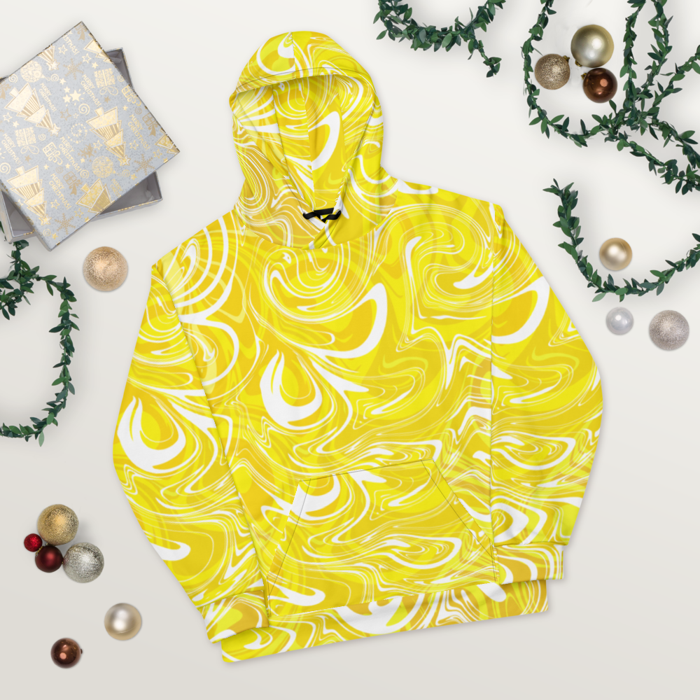 A yellow and white abstract swirl-patterned hoodie lay flat on a light wooden surface. The design features bold, fluid lines that create a vibrant, modern look. The hoodie’s front pocket and hood are visible, showing the seamless all-over print. Festive ornaments, greenery, and wrapped gifts are arranged around it for a decorative, holiday-inspired presentation.