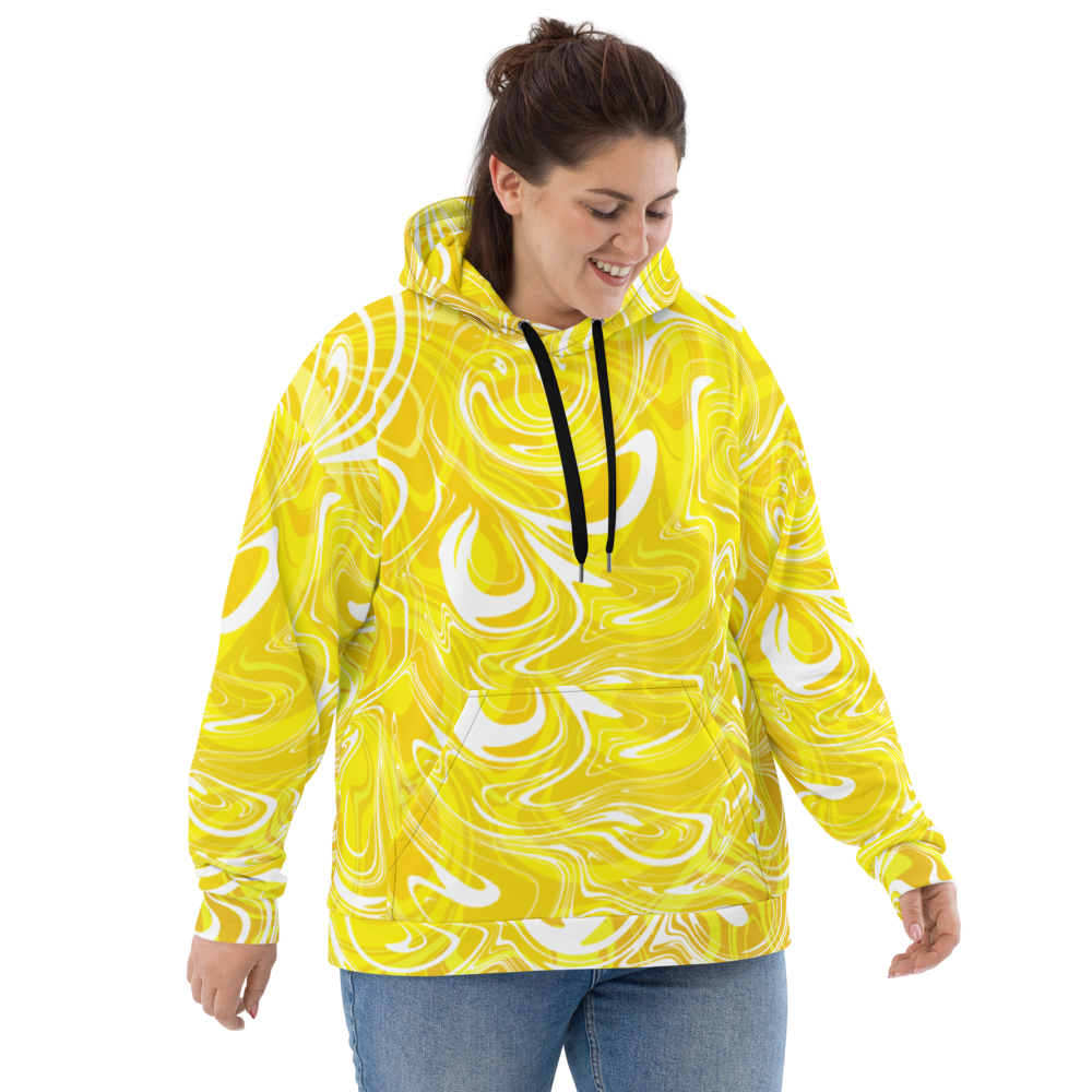 A woman wearing a yellow and white plus-size abstract swirl patterned hoodie with black drawstrings. The hoodie has a relaxed fit and features bold, fluid lines in an artistic, modern design. She is smiling and looking down, showcasing the front of the hoodie against a neutral checkered background.